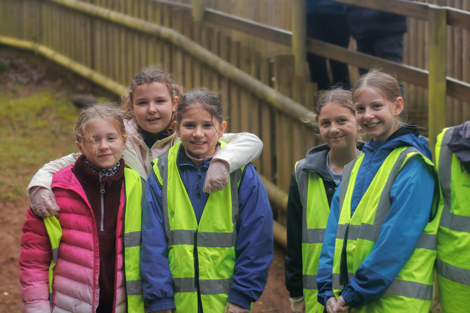 5 workshop children in high vis jackets smile for the camera next to enclosures at woburn safari park 