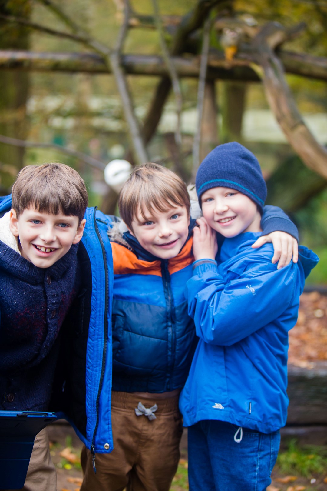 Three happy children in winter clothing look at camera