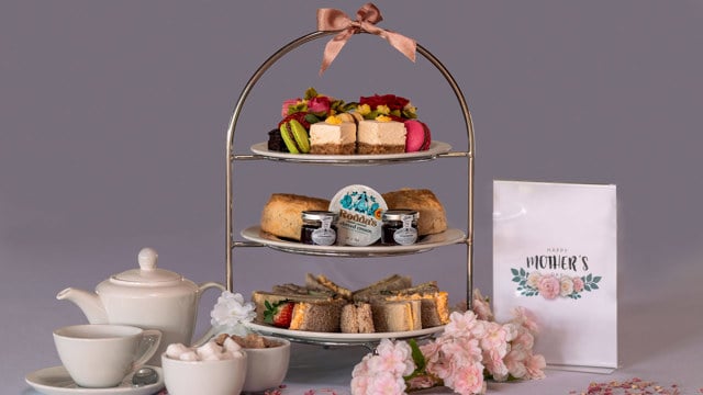 Mother's Day Afternoon Tea laid out on a cake stand, with a teapot and flowers