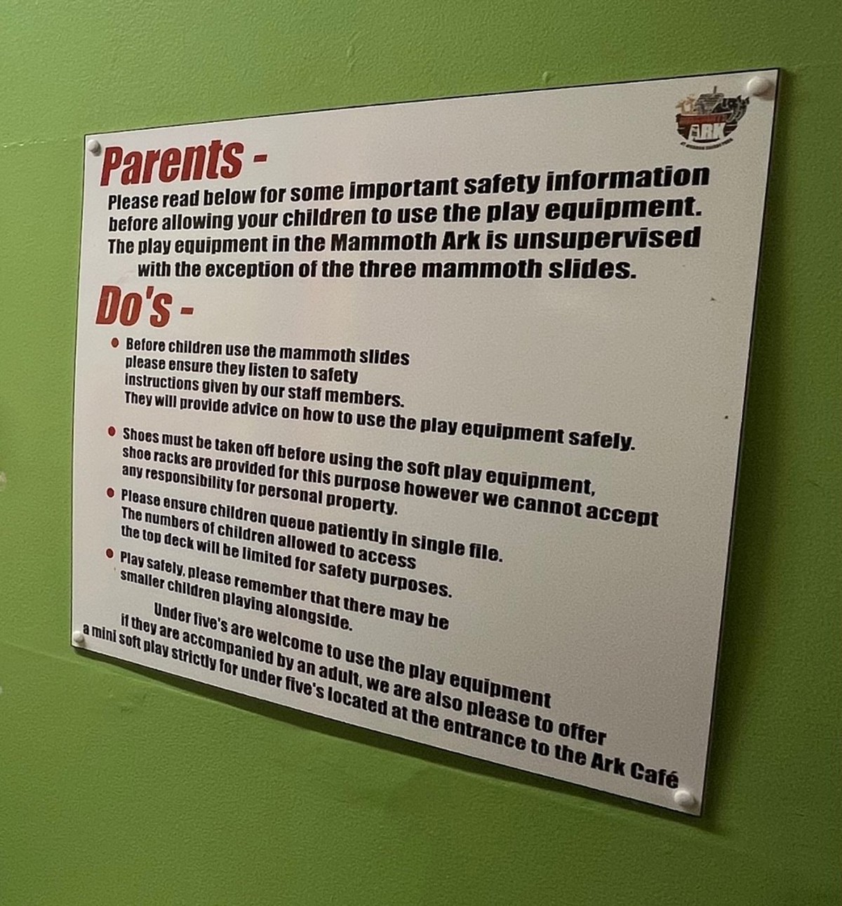 Sign reads Parents ARK Please read below for some important safety information before allowing your children to use the play equipment. The play equipment in the Mammoth Ark is unsupervised with the exception of the three mammoth slides. Do's- Before children use the mammoth slides please ensure they listen to safety Instructions given by our staff members. They will provide advice on how to use the play equipment safely. Shoes must be taken off before using the s play equipment, shoe racks are provided for this purpose however we cannot accept any responsibility for personal property. Please ensure children queue patiently in single file. The numbers of children allowed to access the top deck will be limited for safety purposes. Play safely, please remember that there may be smaller children playing alongside. Under five's are welcome to use the play equipment a mini soft play strictly for under five's located at the entrance to the Ark Café if they are accompanied by an adult'